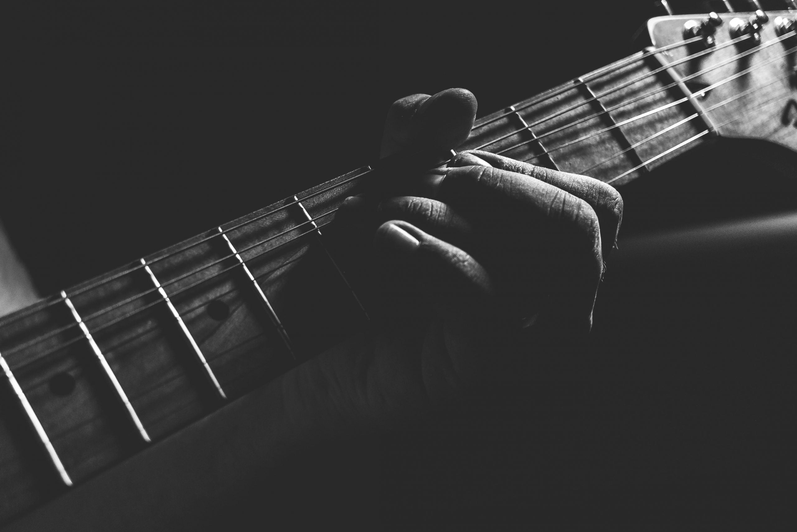 grayscale photo of person holding guitar neck and strings